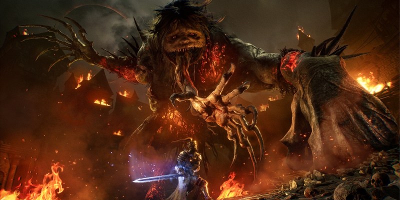 Knight fighting a massive creature in a burning village in Lords of the Fallen.