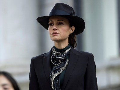 An image of Carla Gugino as Verna in The Fall of the House of Usher showing her standing outside a building wearing all black as part of an article about how Mike Flanagan confirmed her advice would have saved Roderick Usher's children.