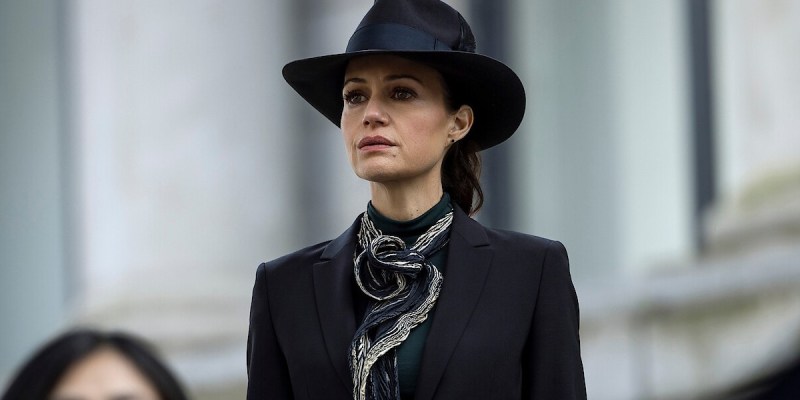 An image of Carla Gugino as Verna in The Fall of the House of Usher showing her standing outside a building wearing all black as part of an article about how Mike Flanagan confirmed her advice would have saved Roderick Usher's children.