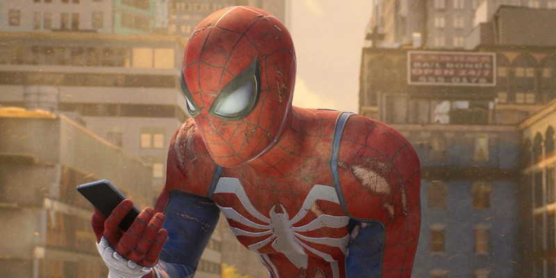 Spider-Man in Marvel's Spider-Man 2, looking at his phone. He's probably reading our ranking of the game's villains.