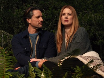 Two characters sitting in a forest. This image is part of an article about when Virgin River Season 6 comes out.