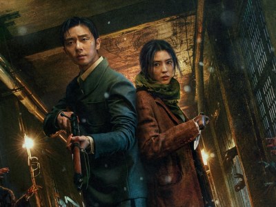 Park Seo-Joon and Han So-Hee hold weapons in a corridor, while hands reach through bars towards them in a still from Gyeongseong Creature.