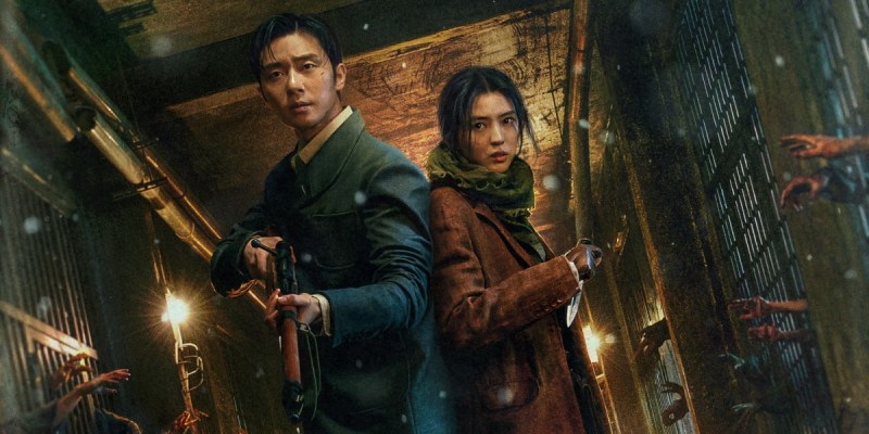 Park Seo-Joon and Han So-Hee hold weapons in a corridor, while hands reach through bars towards them in a still from Gyeongseong Creature.