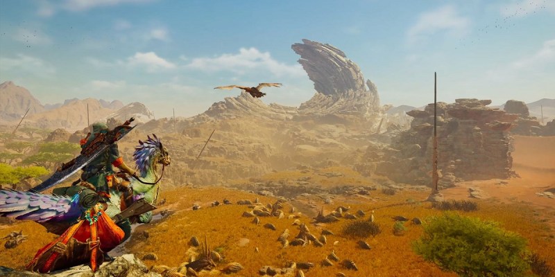 Image of a traveler in monster-like armor riding a bird creature through a rocky desert in Monster Hunter Wilds.