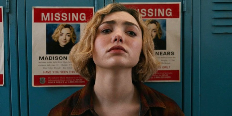 A blonde girl leaning against lockers. The lockers have a picture of her on a missing poster.