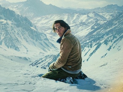 A man on his knees in a snowy mountain landscape.