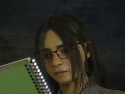 A girl with glasses and brown hair looking at a green notebook.